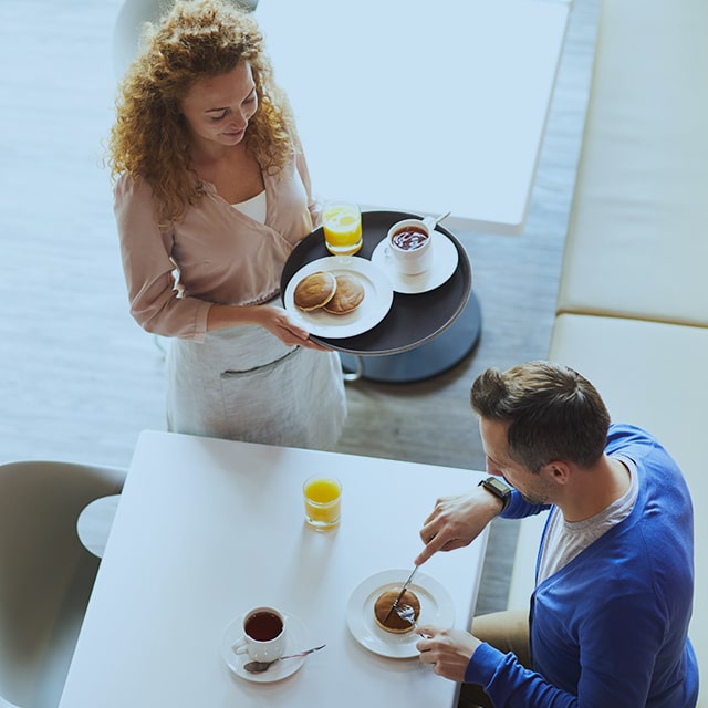 Waitress serving a man breakfast