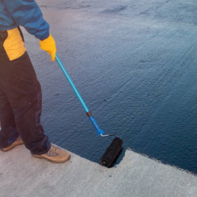 Worker painting the floor with blue